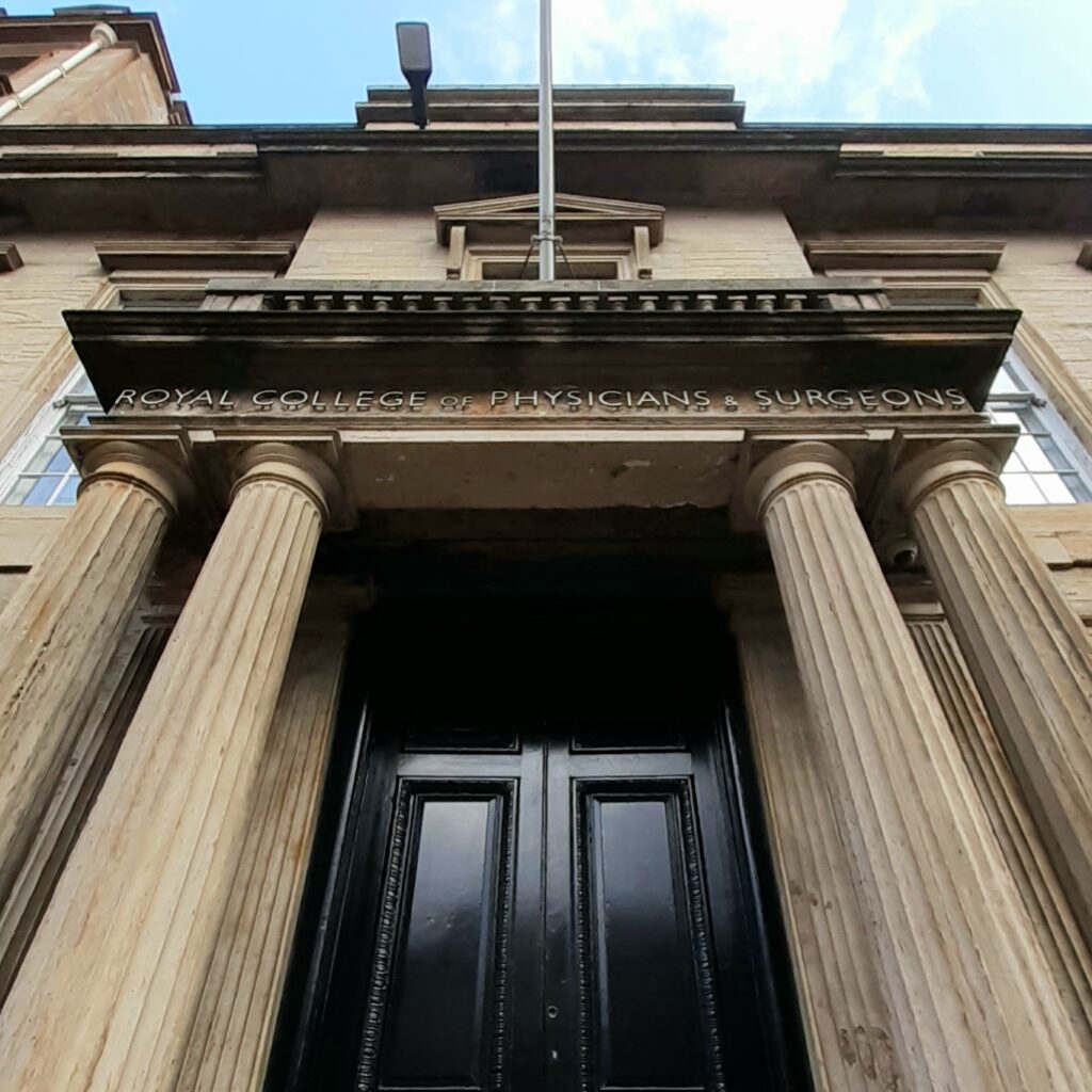 Main entrance to the Royal College of Physicians and Surgeons of Glasgow - Large double doors painted black. They are surrounded by stone columns.